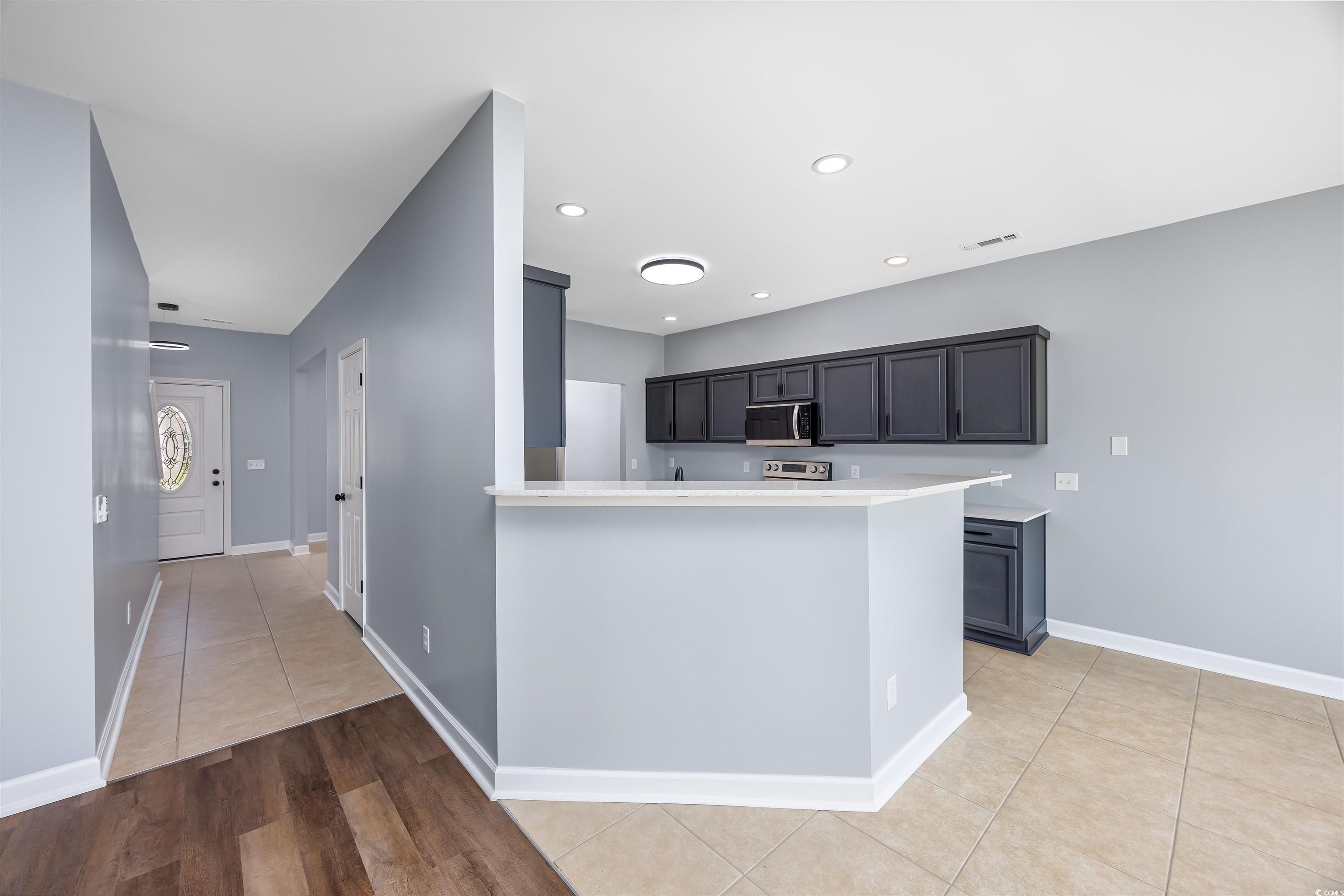1031 Snowberry Drive Longs, SC 29568 - Photo 12 of 38 Kitchen with light tile patterned floors, a peninsula, stainless steel microwave, recessed lighting, and dark cabinetry