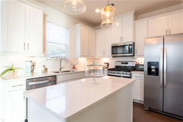 a kitchen with stainless steel appliances granite countertop a sink a stove a refrigerator a center island and cabinets