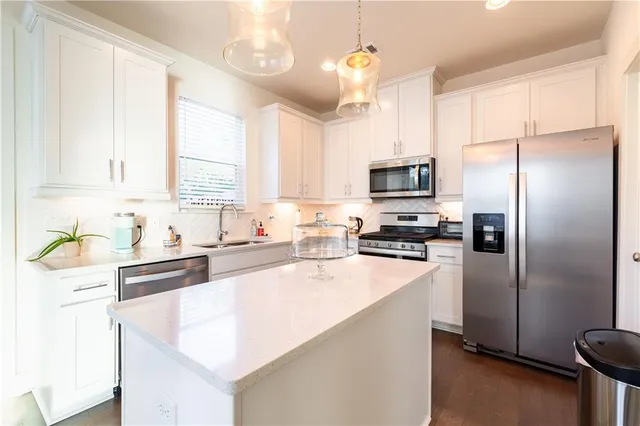 a kitchen with granite countertop a refrigerator a sink a stove a microwave a counter top space and cabinets