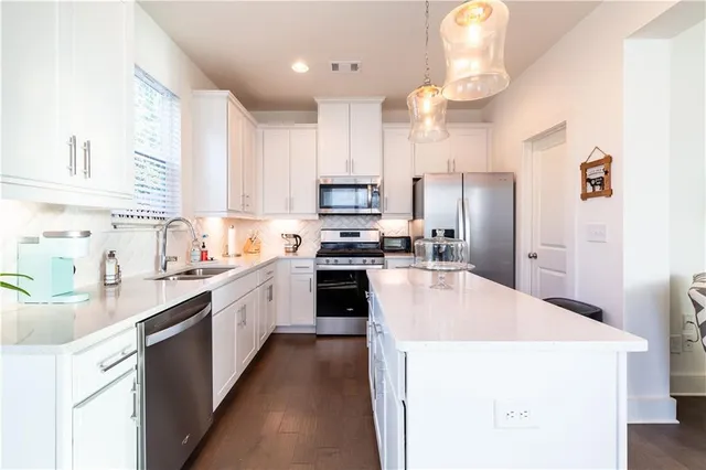 a kitchen with kitchen island granite countertop a sink a counter top space stainless steel appliances and cabinets