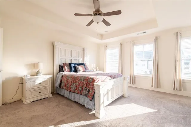 a bedroom with a large bed and a chandelier fan