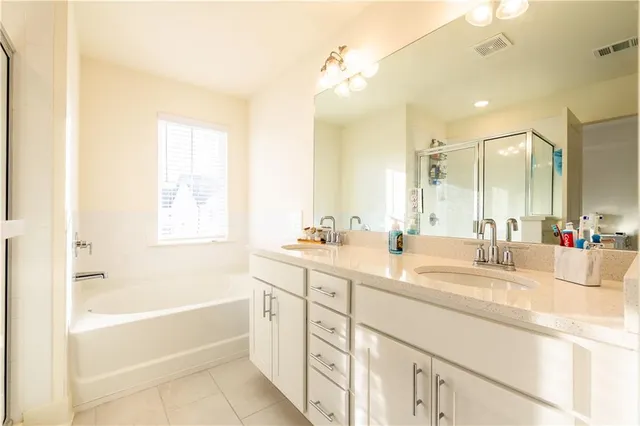 a bathroom with a tub a sink double vanity and a mirror