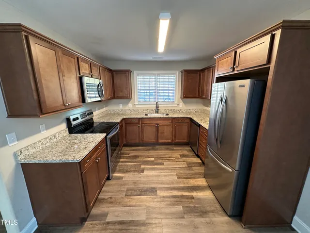 a kitchen with stainless steel appliances granite countertop sink stove refrigerator and cabinets