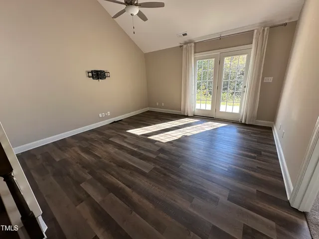 a view of an empty room with a window and wooden floor