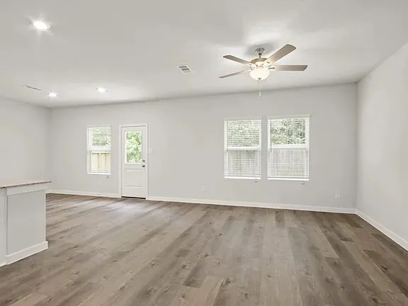 a view of an empty room with a window and wooden floor