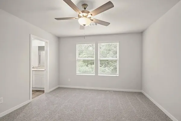 an empty room with windows and ceiling fan