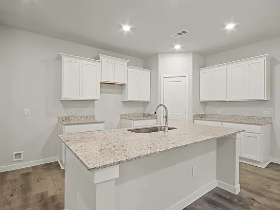 a kitchen with granite countertop white cabinets and a sink