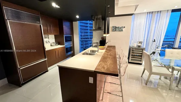 a kitchen with stainless steel appliances kitchen island granite countertop a refrigerator a stove and a sink