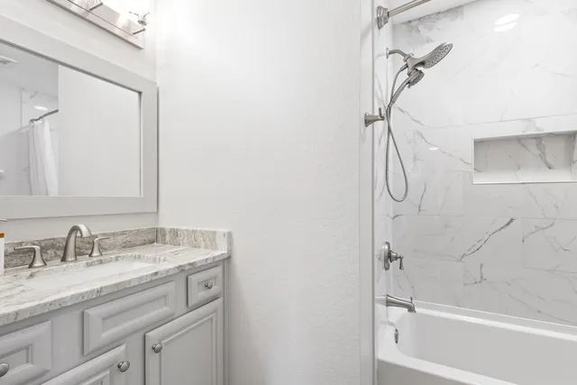 a bathroom with a granite countertop sink a mirror a vanity and a shower