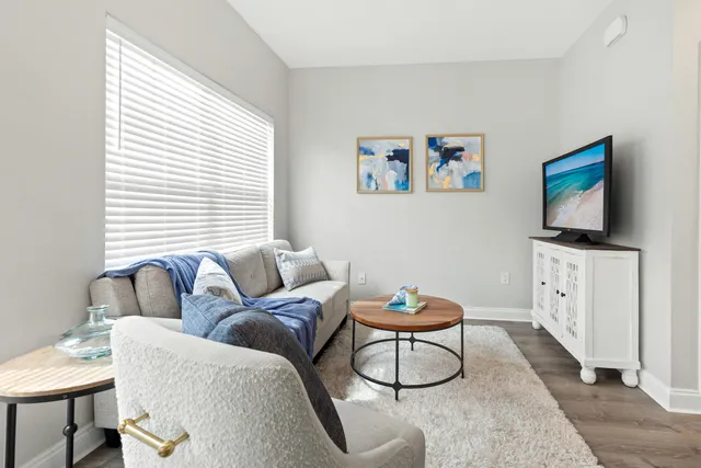 a living room with furniture a flat screen tv and a window