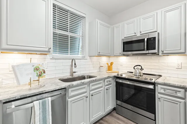 a kitchen with granite countertop a sink stove top oven and microwave