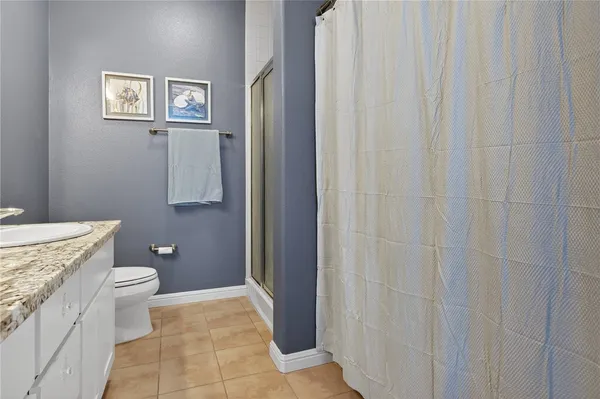 a bathroom with a granite countertop toilet and a sink