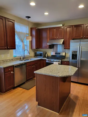 a kitchen with stainless steel appliances granite countertop wooden cabinets a sink a stove a refrigerator and cabinets