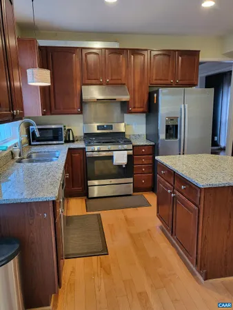 a kitchen with stainless steel appliances granite countertop a stove a sink and a refrigerator