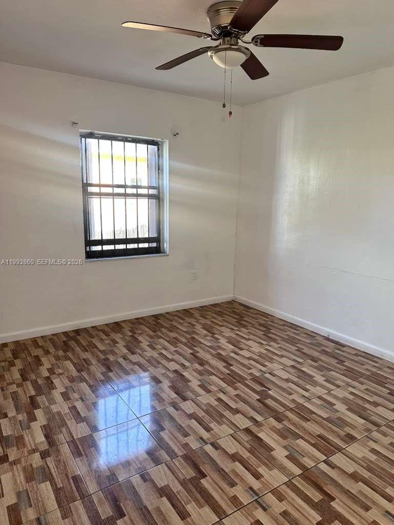 576 Northwest 147th Street, Unit 576 Miami, FL 33168 - Photo 5 of 18 an empty room with wooden floor fan and windows