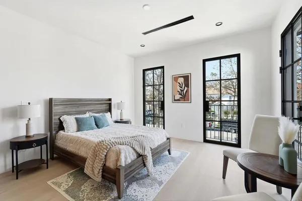 a bedroom with a large bed couch and two windows