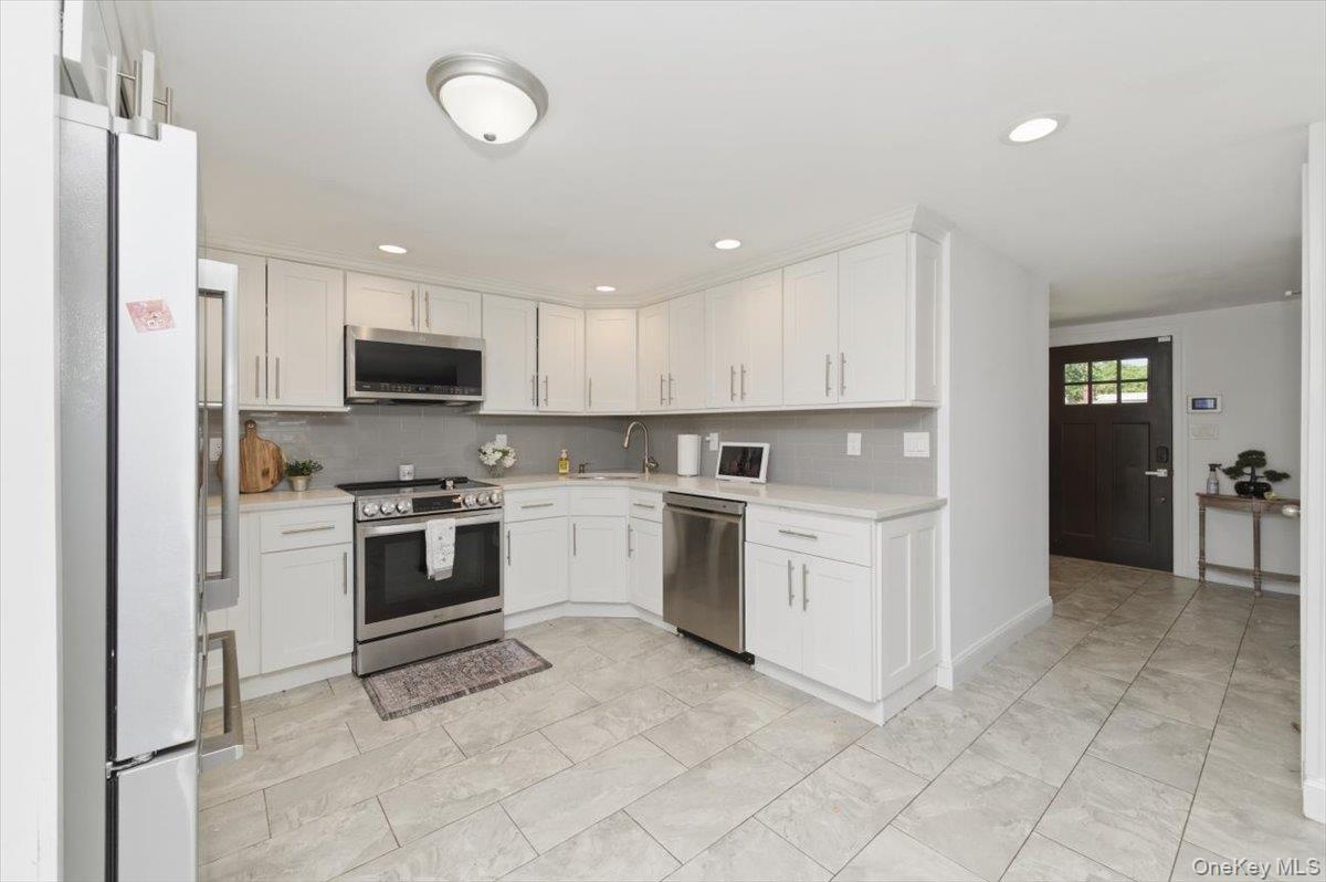 10 Rutgers Road Farmingville, NY 11738 - Photo 9 of 27 a kitchen with white cabinets and white appliances