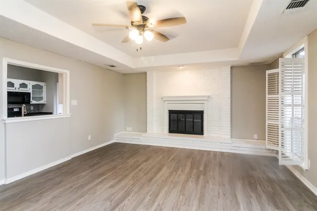 a view of an empty room with wooden floor fireplace and a window