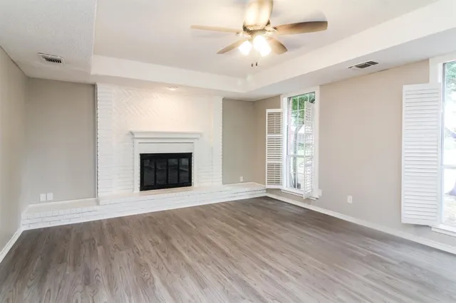 an empty room with wooden floor fan and windows