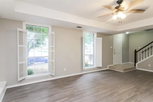 a view of an empty room with a window and wooden floor