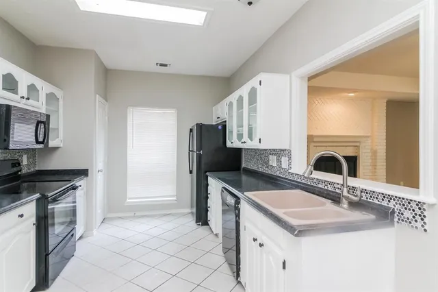 a kitchen with granite countertop a sink stove top oven and refrigerator