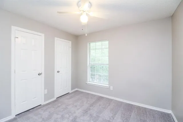 an empty room with a chandelier fan and windows