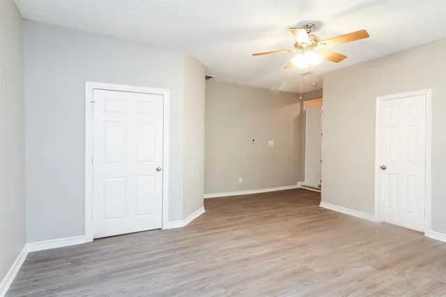 an empty room with wooden floor and a ceiling fan