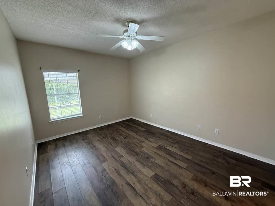 2651 South Juniper Street, Unit 401 Foley, AL 36535 - Photo 22 of 27 Spare room featuring a textured ceiling, a ceiling fan, baseboards, and dark wood finished floors