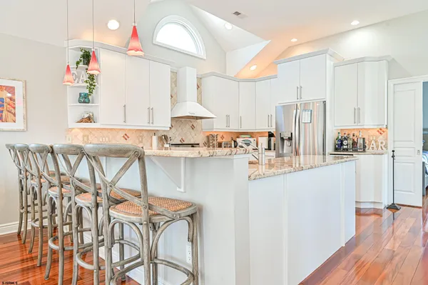 a kitchen with stainless steel appliances granite countertop a sink stove and white cabinets with wooden floor