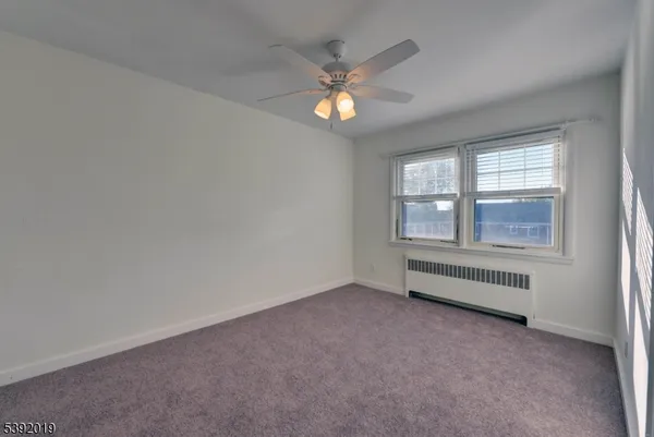 an empty room with chandelier fan and windows