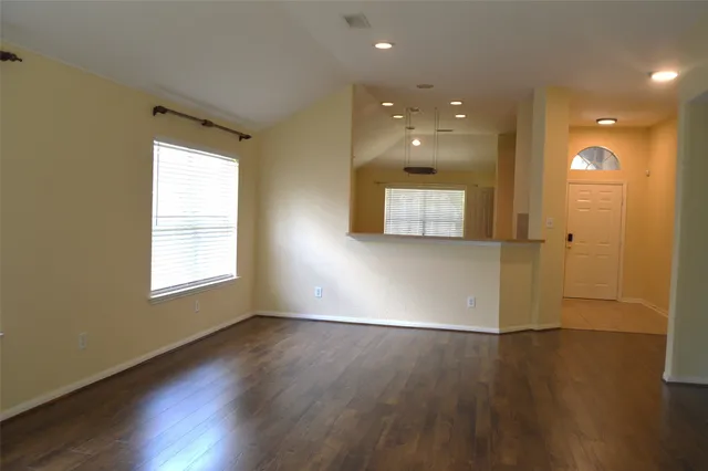 an empty room with wooden floor a fireplace and windows