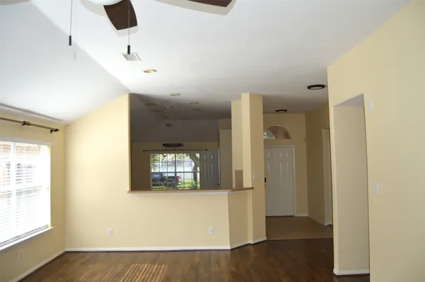 an empty room with wooden floor a fireplace and windows