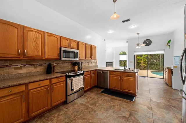 a kitchen with stainless steel appliances granite countertop a stove top oven a sink dishwasher a dining table and chairs with wooden floor