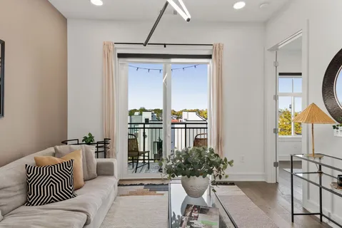 a living room with furniture potted plant and kitchen view
