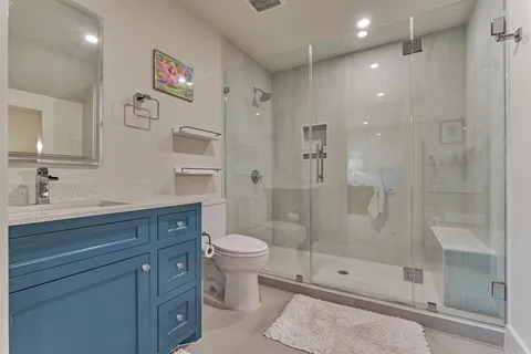 a bathroom with a shower sink vanity mirror and toilet