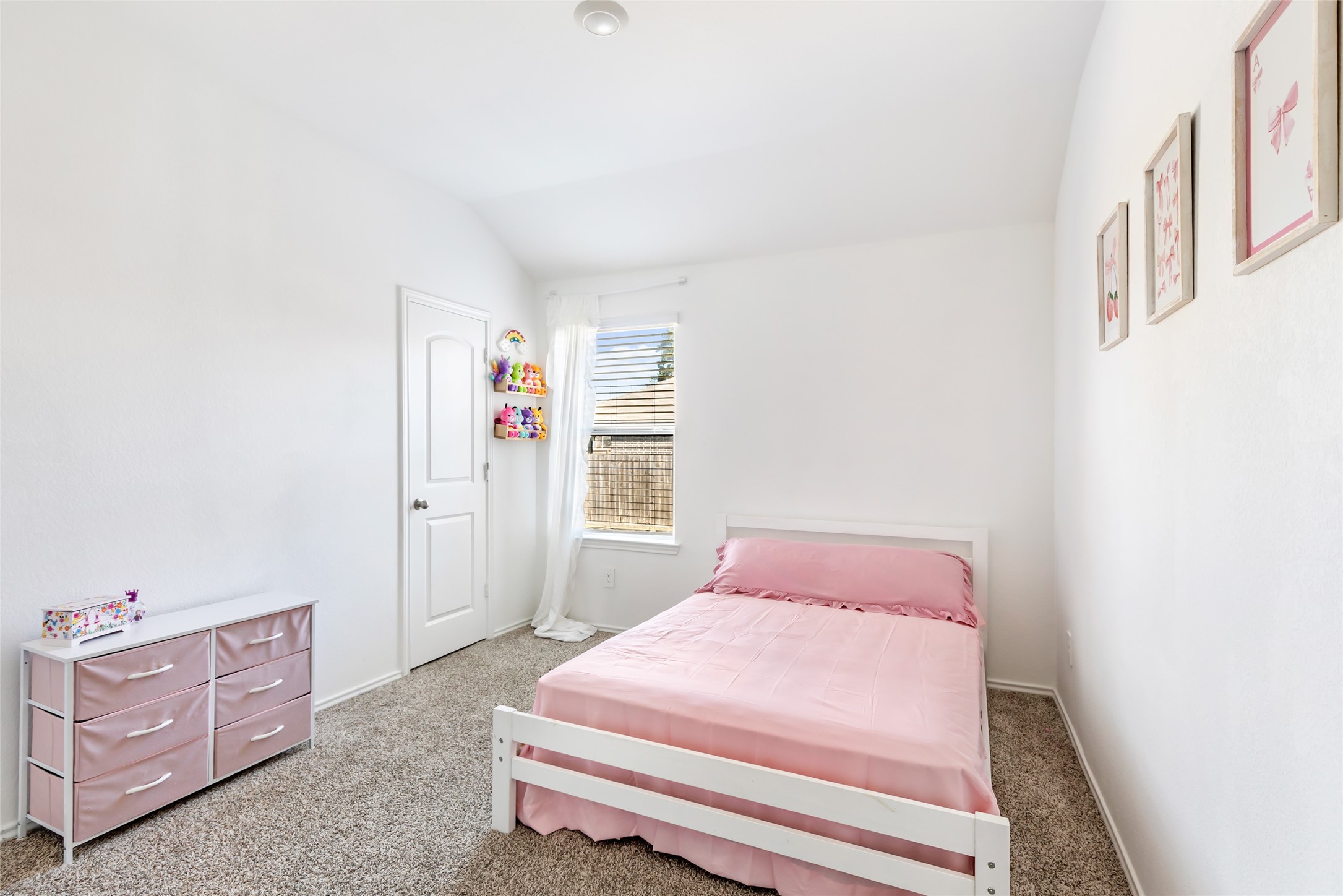811 Republic Road New Caney, TX 77357 - Photo 21 of 37 This bedroom is bright and cozy, featuring a single bed with pink bedding, a white dresser with pink drawers, and carpeted flooring. The room is well-lit by a window and decorated with simple wall art, creating a welcoming space.