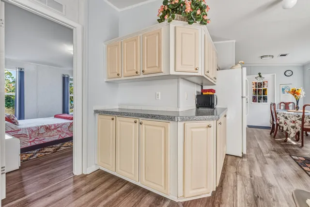 a kitchen with white cabinets and wooden floor