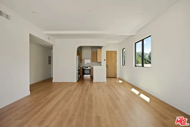 a view of empty room with wooden floor and window