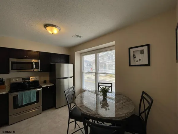 a kitchen with a table chairs refrigerator and microwave