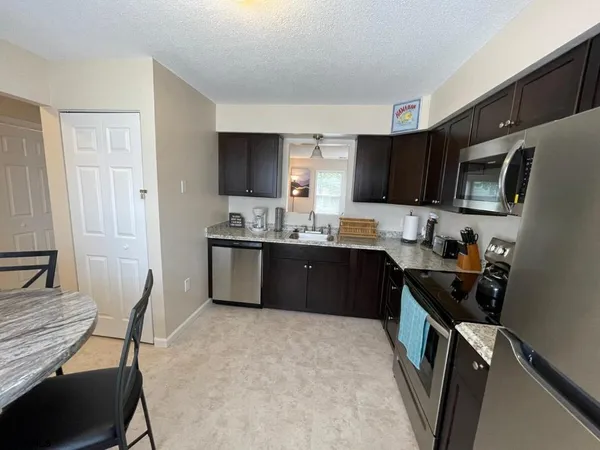 a kitchen with a sink a stove a refrigerator a microwave a dining table and chairs