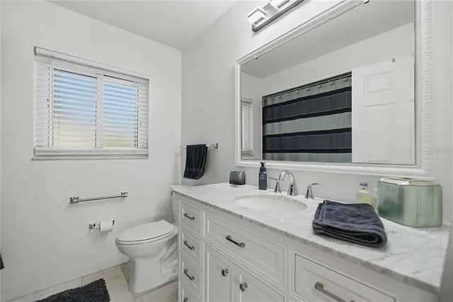 a bathroom with a granite countertop toilet sink and mirror
