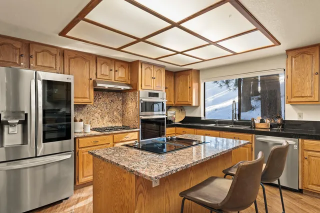 a kitchen with stainless steel appliances granite countertop a sink and a refrigerator