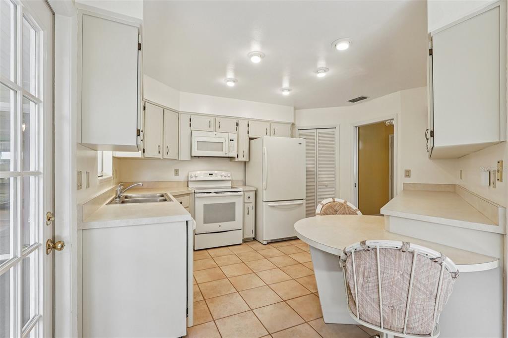 305 Brigadoon Circle Leesburg, FL 34788 - Photo 16 of 38 a kitchen with a sink a refrigerator and white cabinets