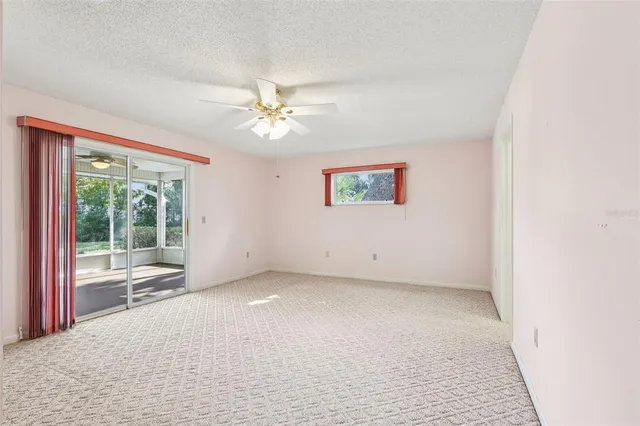 en empty room with windows and ceiling fan