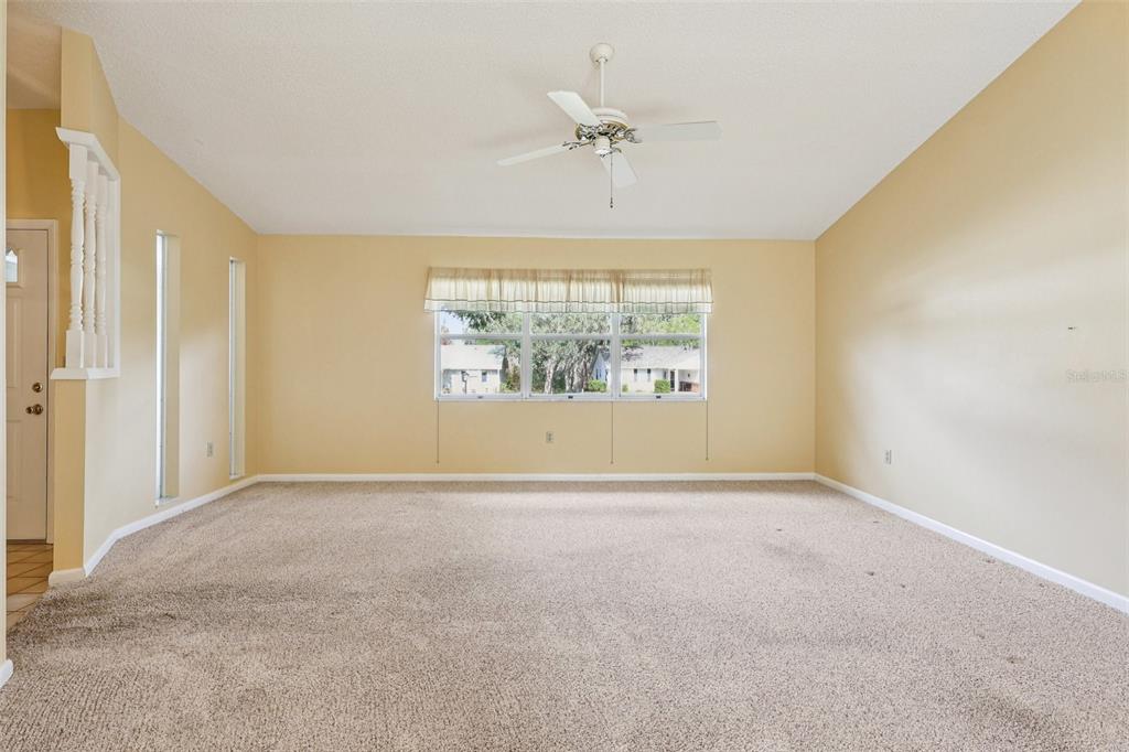 305 Brigadoon Circle Leesburg, FL 34788 - Photo 7 of 38 an empty room with windows and chandelier fan