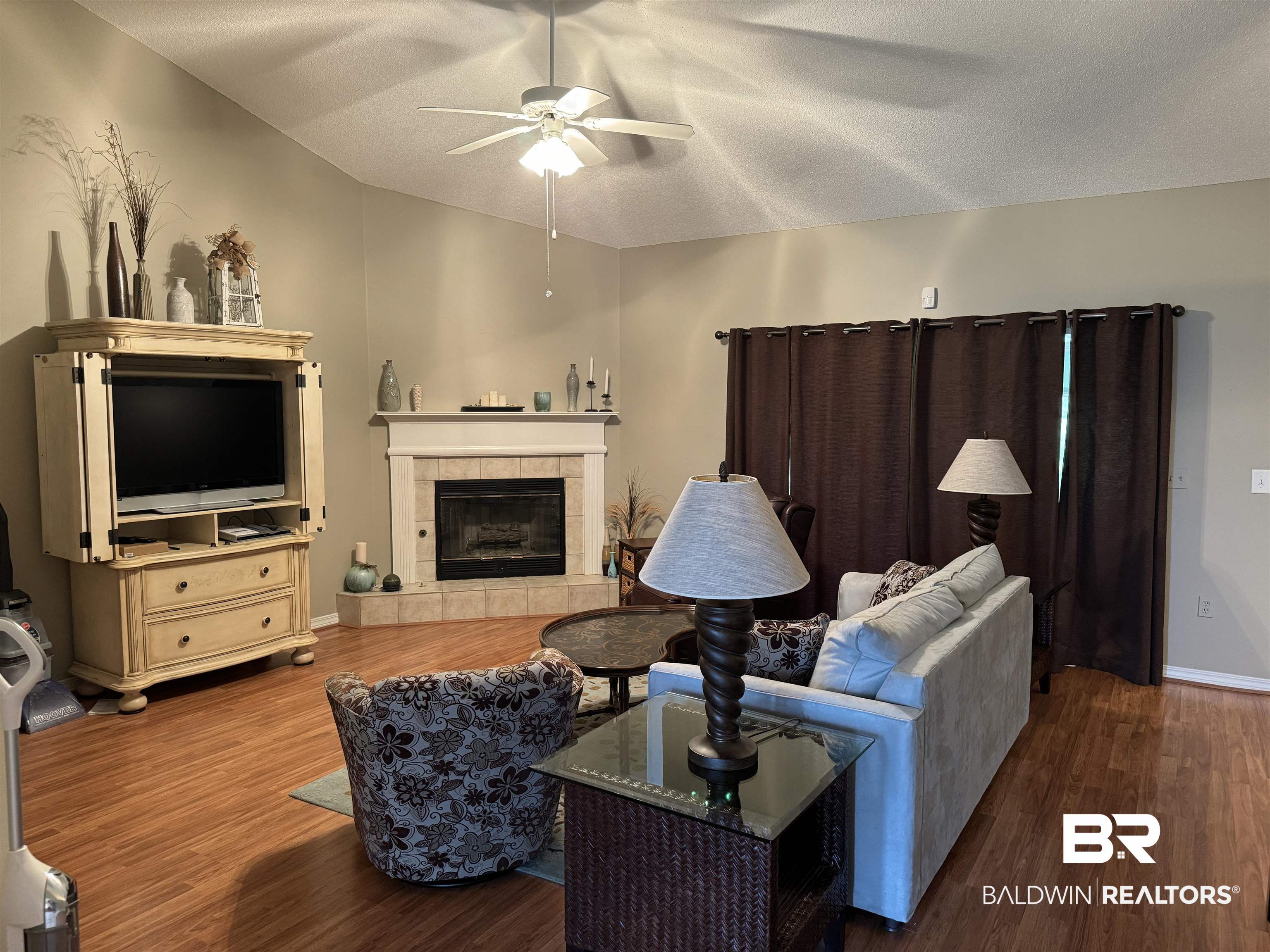 9139 Clubhouse Drive Foley, AL 36535 - Photo 10 of 30 Living room featuring a textured ceiling, a tile fireplace, hardwood / wood-style flooring, and ceiling fan