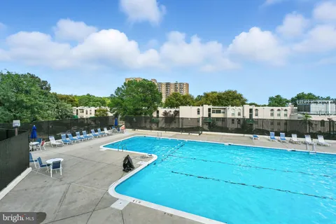 a view of a swimming pool with lawn chairs under an umbrella