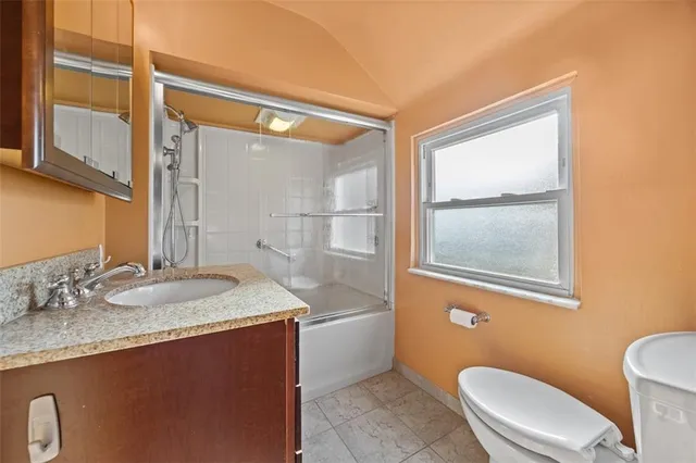 a bathroom with a granite countertop sink toilet a mirror and shower