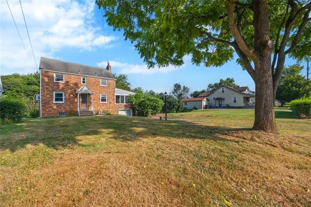 a view of a house with a big yard and large trees