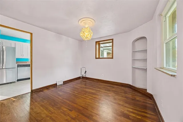 a view of empty room with wooden floor and window